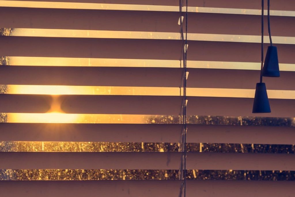 A glimpse of sunset on the window with wood blinds